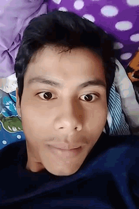 a young man is laying on a bed with a polka dot pillow