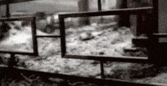 a black and white photo of a metal fence with a blurred background .
