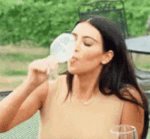a woman is drinking a glass of wine from a glass .