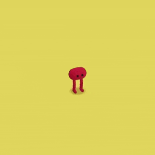 a red cartoon character is standing on a yellow background .