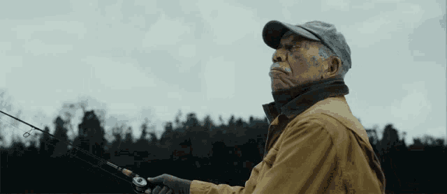a man in a hat is holding a fishing rod in his hand