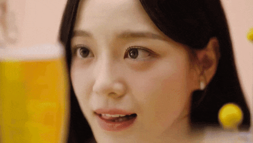 a close up of a woman 's face with a yellow bottle in the background .