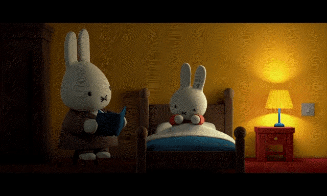 a stuffed bunny is reading a book to another stuffed bunny in bed
