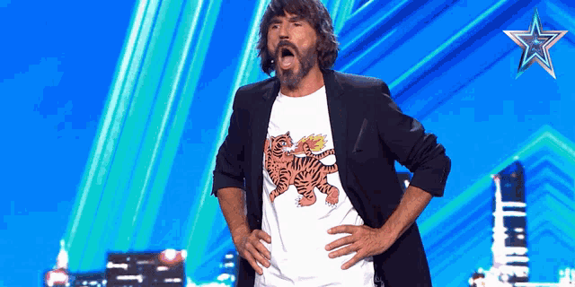 a man wearing a t-shirt with a tiger on it stands on a stage with his hands on his hips