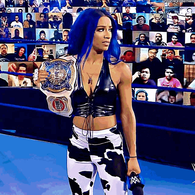 a woman with blue hair is holding a wrestling championship belt and a microphone