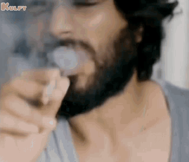 a man with a beard is smoking a cigarette with smoke coming out of it .