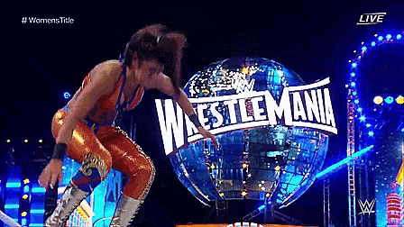a woman is jumping in the air in front of a wrestlemania sign