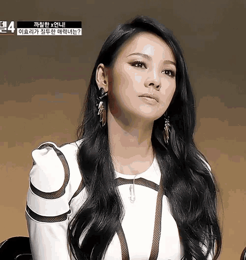 a woman with long black hair is wearing earrings and a white shirt