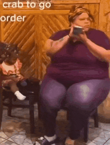 a woman in a purple shirt is sitting on a stool holding a cell phone with the words crab to go order above her