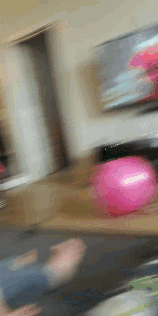a pink ball is sitting on a wooden table in a blurry photo