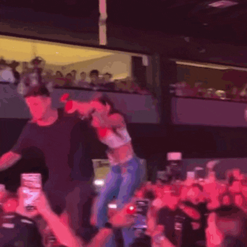 a man and a woman are dancing on a stage in front of a crowd of people