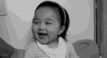 a black and white photo of a baby girl laughing and crying .