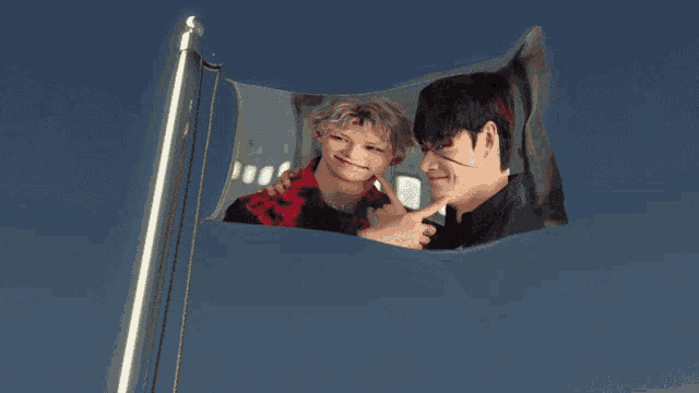 a flag with a picture of two men on it against a blue sky