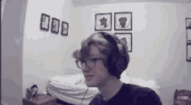 a young man wearing headphones and glasses is standing in a room .