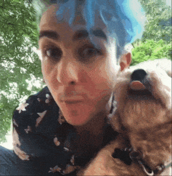 a woman with blue hair is holding a dog