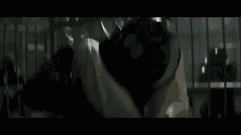 a man with white hair is fighting another man in a cage .