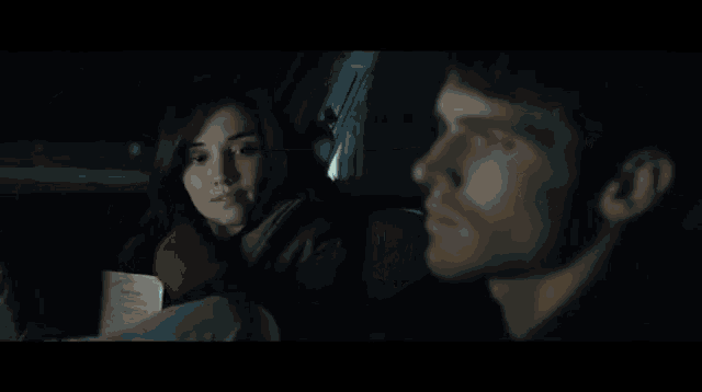 a man and a woman are looking at each other in a car