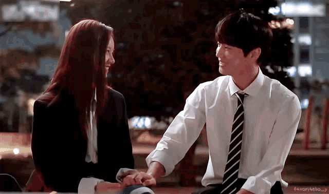 a man and a woman are holding hands and looking at each other .
