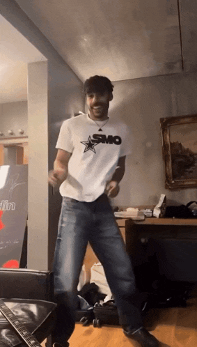 a man wearing a smo shirt is dancing in a room