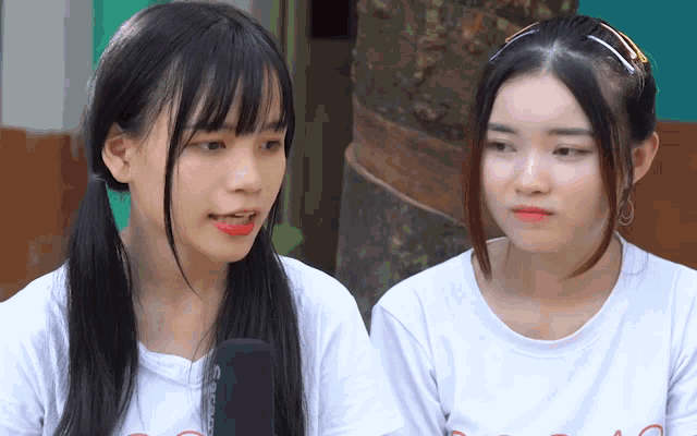 two girls are sitting next to each other with one wearing a shirt that says ' ao ' on it