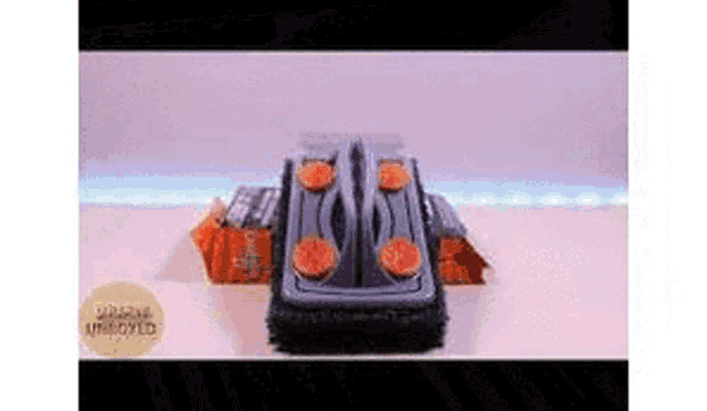 a toy car with orange wheels is sitting on top of a white table .