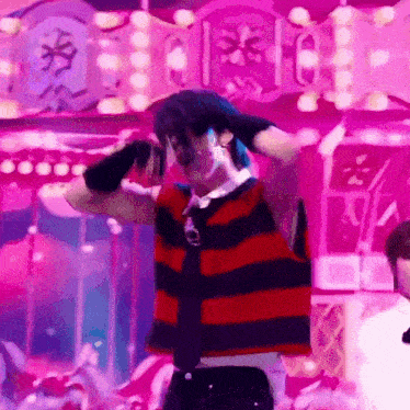 a man in a red and black striped shirt and tie is dancing in front of a crowd .