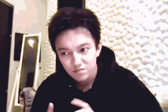 a young man in a black hoodie looks at the camera