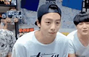 a young man wearing a baseball cap and a white t-shirt is looking at the camera .