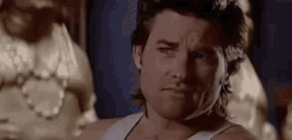 a man in a white tank top is making a face .