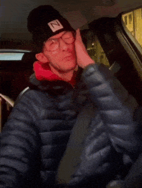 a man wearing a beanie with the letter n on it is sitting in a car