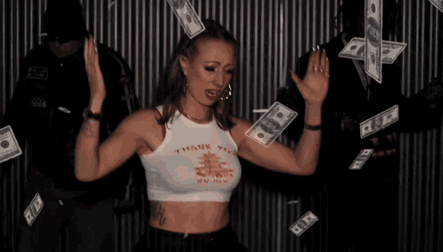 a woman in a crop top that says thank you is dancing with money falling around her