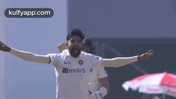 a cricket player is celebrating with his arms outstretched .