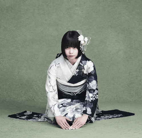 a woman in a black and white kimono is kneeling down
