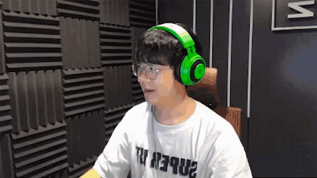 a man wearing green headphones and glasses is sitting in a chair in front of a wall .