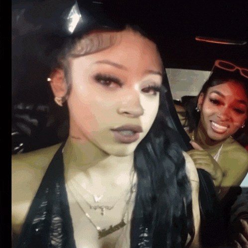 two women are sitting in a car and one is wearing a necklace that says ' i love you ' on it