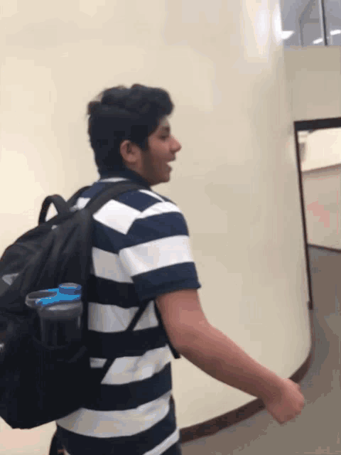 a man in a striped shirt is carrying a backpack
