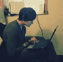 a man sits in front of a laptop computer