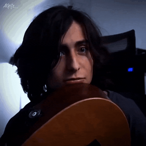a close up of a man holding a guitar with the letters agi 's on the bottom