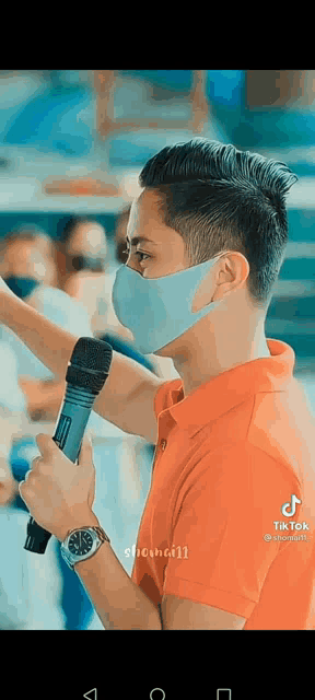 a young man wearing a mask is holding a microphone .