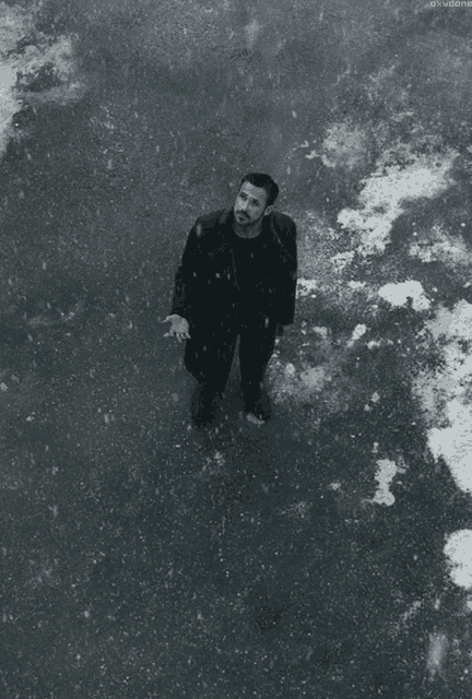 a man in a black coat is standing on a snowy street