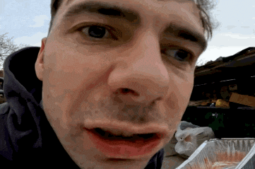 a close up of a man 's face with a plastic container behind him