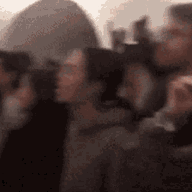 a blurry picture of a group of people standing next to each other drinking beer .