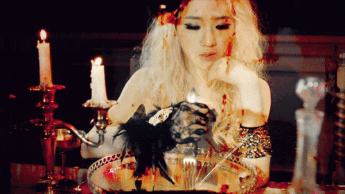 a woman is sitting at a table with candles and a bowl of food