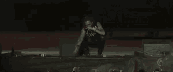 a man is kneeling on a stage with a microphone in his hand .