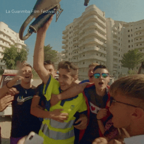 a group of young men are gathered around a man holding a trophy and the words la guarimba film festival are on the bottom