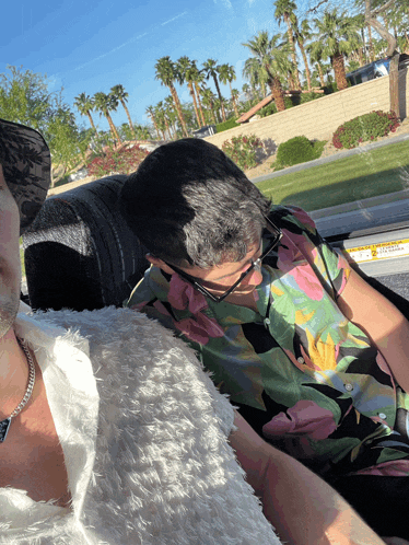 a man in a floral shirt is sitting next to a woman in a white dress