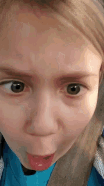 a young girl is making a funny face with her tongue out
