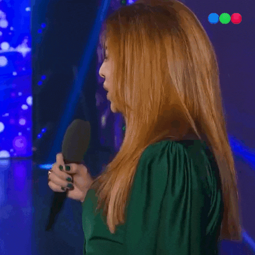 a woman in a green shirt holds a microphone and laughs