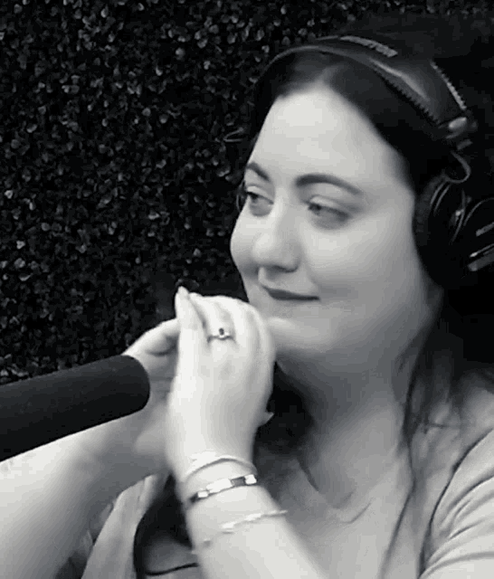 a woman wearing headphones and a ring looks at the camera