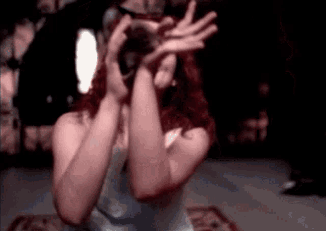 a woman is covering her face with her hands in a dark room
